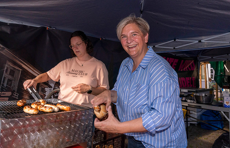 Melanie Witte-Lonsing hilft an einem Grillstand und bereitet ein Wurstbrötchen vor.