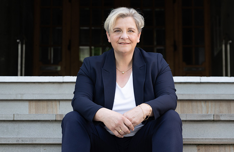 Melanie Witte-Lonsing in einem blauen Blazer auf einer Treppe sitzend