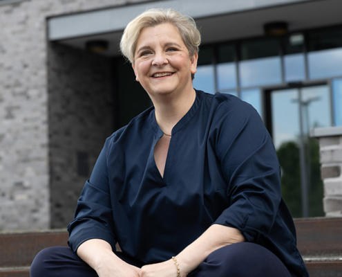 Melanie Witte-Lonsing sitzt auf einer Treppe und lächelt in die Kamera