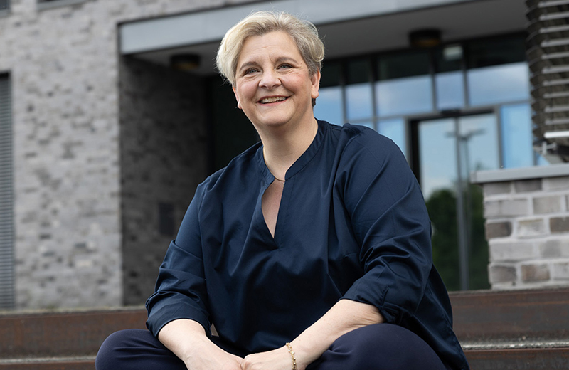 Melanie Witte-Lonsing sitzt auf einer Treppe und lächelt in die Kamera